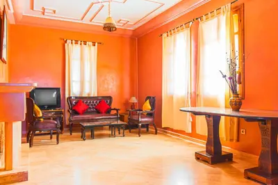 a living room with orange walls and a table and chairs at Villa 36 Amelkis - Pool & Garden in Marrakech