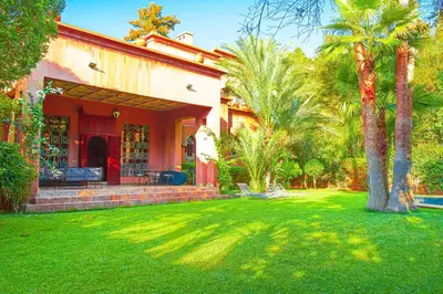 a house with palm trees in front of a yard at Villa 36 Amelkis - Pool & Garden in Marrakech