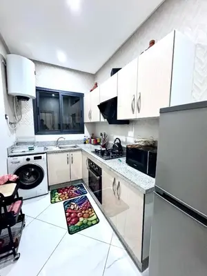 a kitchen with white cabinets and a plate of fruit on the floor at Appartement sympathique in Marrakech