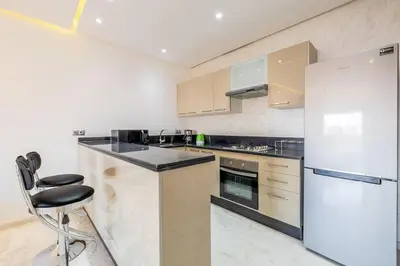 a kitchen with a white refrigerator and a counter at Appartement haut standing au centre de Marrakech in Marrakech