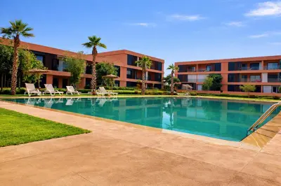 a large swimming pool in front of a building at Appartement Moderne, Vue Atlas & Piscine, Noria in Marrakech