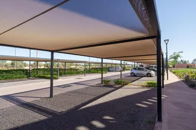 a parking lot with a car parked under a canopy at Appartement Moderne, Vue Atlas & Piscine, Noria in Marrakech