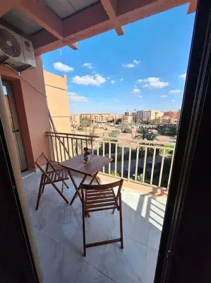 a table and chairs on a balcony with a view at Jardin Majorel Appartement en résidence fermée in Marrakech