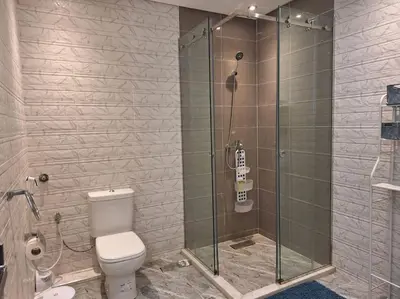 a bathroom with a toilet and a glass shower at Jardin Majorel Appartement en résidence fermée in Marrakech