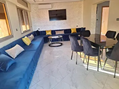 a living room with a blue couch and a table at Jardin Majorel Appartement en résidence fermée in Marrakech