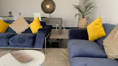 a living room with two blue couches with yellow pillows at Appartement au cœur de Marrakech in Marrakech