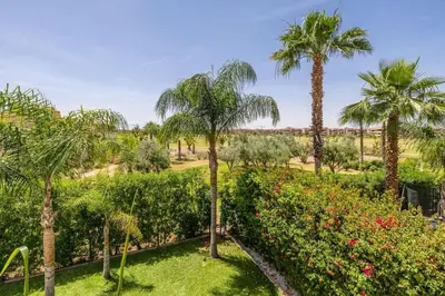 a view of a garden with palm trees and flowers at Villa sur golf avec piscine privée chauffée in Marrakech