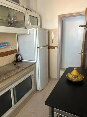 a kitchen with a black table and a white refrigerator at Appartement Cosy & Calme à Izdihar Confort Assuré in Marrakech