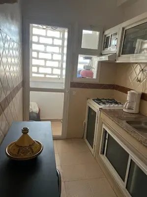 a small kitchen with a table and a stove at Appartement Cosy & Calme à Izdihar Confort Assuré in Marrakech