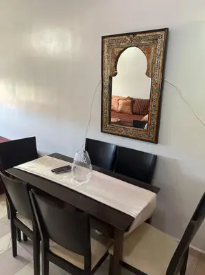 a table with chairs and a mirror on the wall at Appartement Cosy & Calme à Izdihar Confort Assuré in Marrakech