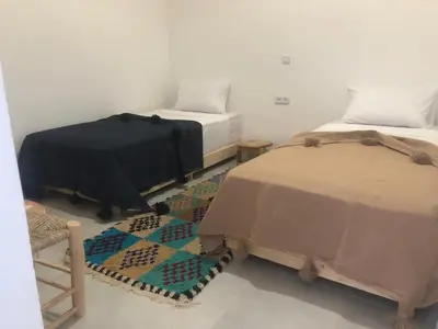 a room with two beds and a rug at Riad Nomad House Marrakech in Marrakech