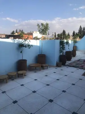 a patio with benches and a blue wall with trees at Riad Nomad House Marrakech in Marrakech