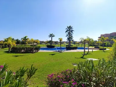 a park with a pool and palm trees and flowers at Appartement de vacances à Prestigia golf city rez jardin in Marrakech
