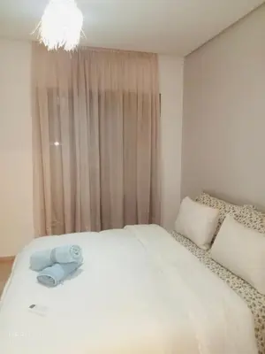 a bedroom with a large white bed with a window at Appartement de vacances à Prestigia golf city rez jardin in Marrakech