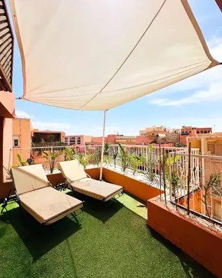 a patio with two chairs and an umbrella on a balcony at Magnifique 2 chambres Terrasse et Wifi à Marrakech in Marrakech