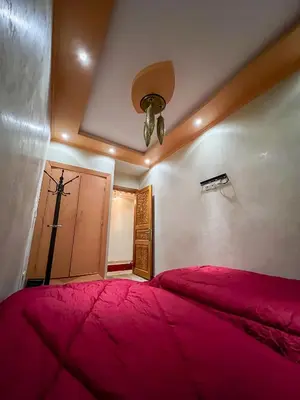 a bedroom with a red bed and a cross on the wall at Superbe Appartement en Résidence, Marrakech Guiliz in Marrakech