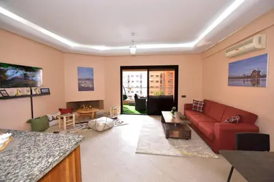 a living room with a red couch and a table at Cozy Apartment in Hay Charaf district, Marrakech in Marrakech