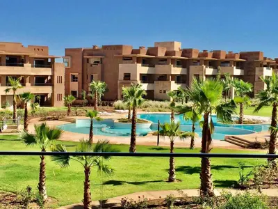 a resort with palm trees in front of a building at Prestigia appartement in Marrakech