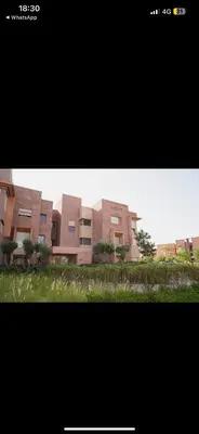a picture of a building with grass in front of it at Appartement Marrakech prestigia by Sofia 2 chambres piscine in Marrakech