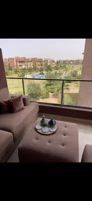 a living room with a couch and a large window at Appartement Marrakech prestigia by Sofia 2 chambres piscine in Marrakech