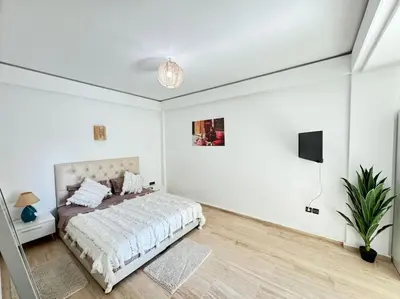 a white bedroom with a bed and a tv at Appart cozy hyper centre calme in Marrakech