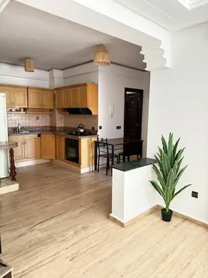 a large kitchen with wooden floors and a table at Appart cozy hyper centre calme in Marrakech