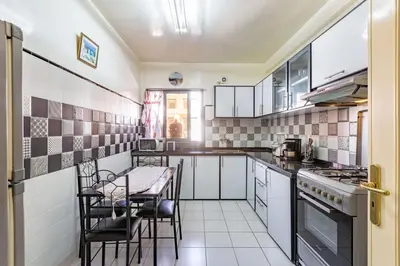 a kitchen with white cabinets and a table and chairs at Appartement Duplex confort qualité très bien situé in Marrakech