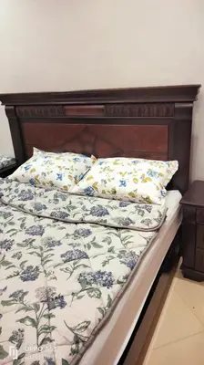 a bed with a wooden head board with blue flowers at Assala GUÉLIZ in Marrakech