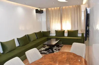 a living room with a green couch and a table at Assala GUÉLIZ in Marrakech