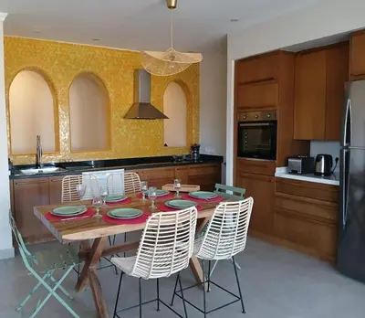 a kitchen with a wooden table with chairs around it at Appartement Palmeraie avec terrasse in Marrakech