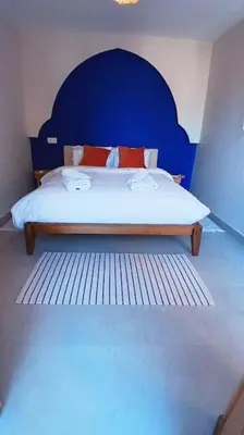 a bedroom with a bed with a blue headboard at Appartement Palmeraie avec terrasse in Marrakech