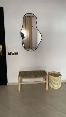 a mirror and a bench in front of a wall at Familial Cosy Appart in Marrakech