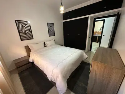 a bedroom with a white bed and a table at Familial Cosy Appart in Marrakech