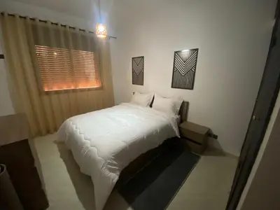 a bedroom with a bed with white sheets and a window at Familial Cosy Appart in Marrakech