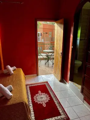 a red room with a bed and a door to a patio at Riad Mido in Marrakech