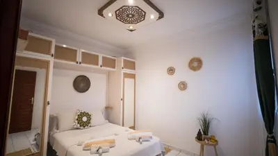 a white bedroom with two beds and a chandelier at Riad kechin in Marrakech