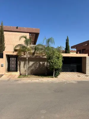 a building with a garage with a palm tree in front of it at Villa à marrakech avec piscine in Marrakech