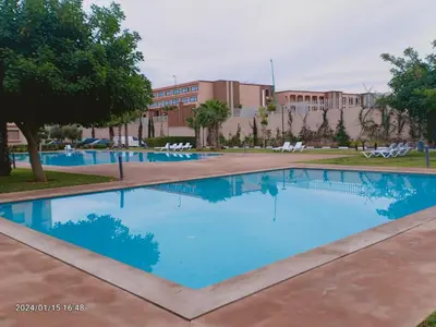 a pool with blue water in front of a building at Marrakech Luxury ATLAS in Marrakech