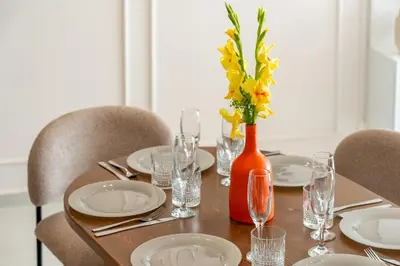 a table with plates and glasses and a vase with flowers at Luxe Urbain - 3 Chambres en Centre-Ville in Marrakech