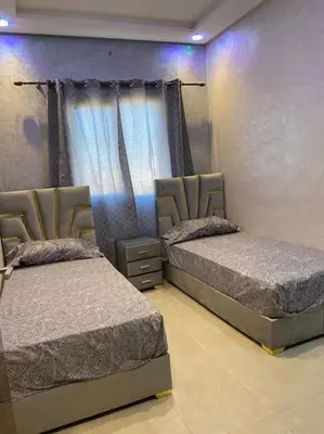 two beds in a room with purple walls at Au cœur de la Ville Rouge in Marrakech