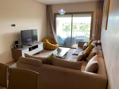 a living room with a large couch and a television at Prestigia Aparts de Vacances by Sabor Voyage in Marrakech