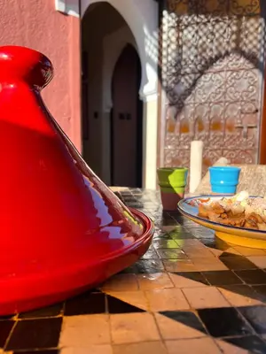 a red vase sitting on a table with a plate of food at Un rêve à Marrakech in Marrakech