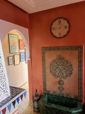 a clock hanging on a wall with a fireplace at Un rêve à Marrakech in Marrakech