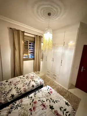 a bedroom with two beds and a chandelier at Marrakech Airport Appart in Marrakech