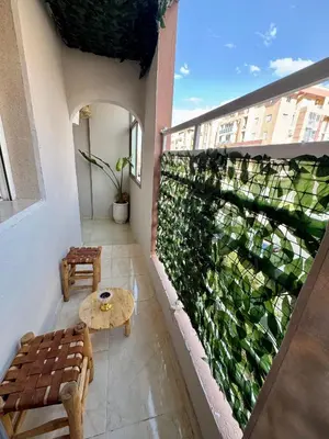 a balcony with a green wall with a table and benches at Marrakech Airport Appart in Marrakech