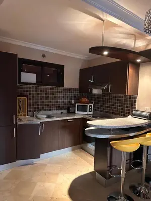 a kitchen with brown cabinets and a counter top at Appartement meublé à River palm in Marrakech