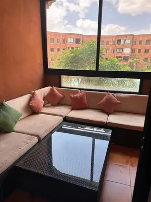a living room with a couch and a large window at Appartement meublé à River palm in Marrakech