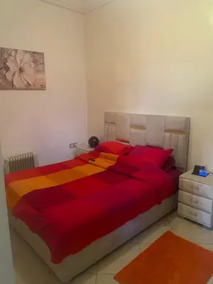 a bedroom with a bed with a red and orange blanket at Apparemment tout confort in Marrakech