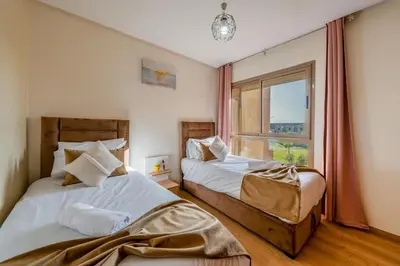 two beds in a bedroom with a window at Exceptional Golf Apartment - 2 Bedrooms Prestigia Marrakech in Marrakech