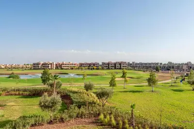 a green field with trees and buildings in the background at Exceptional Golf Apartment - 2 Bedrooms Prestigia Marrakech in Marrakech